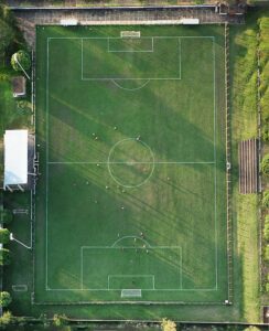 Drone shot capturing a soccer match on a vibrant green field with players in action.