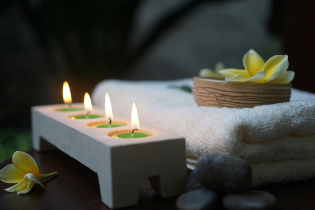 Relaxing spa scene featuring flickering candles, soft towels, and fresh flowers.
